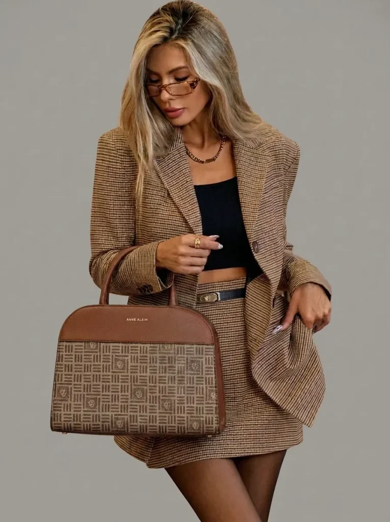 Mujer con conjunto de blazer y falda a cuadros y bolso estructurado, look de estilo Tailored.